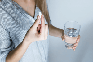 woman taking a probiotic with water